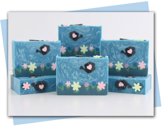 Soap with flowers and watering can in a blue sky