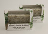 Bars of soap in custom packaging with peppermint leaves in a white bar