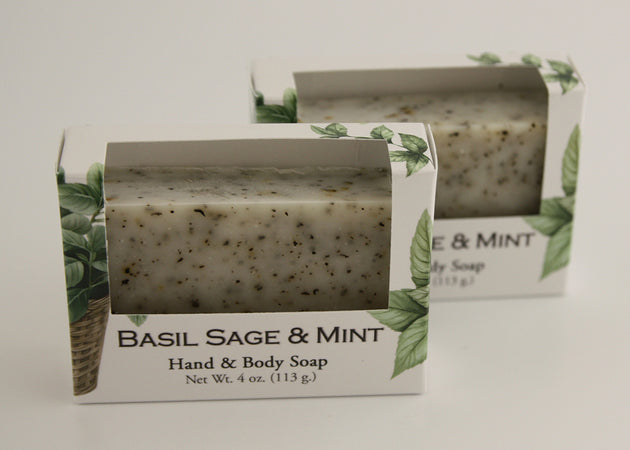 Bars of soap in custom packaging with peppermint leaves in a white bar