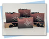 Black to plum ombre bars of soap with black flowers on top and a white outline rose stamp on the bar