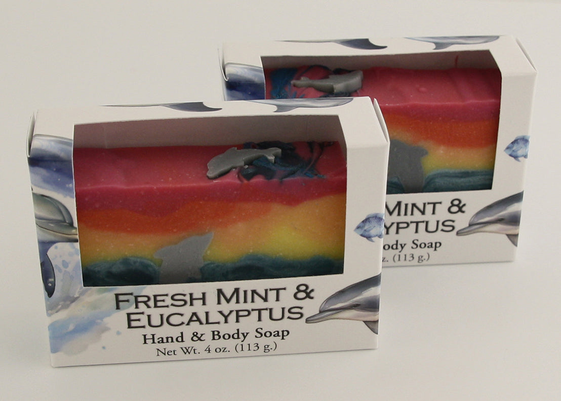 Bars of soap in custom packaging with with a dolphin jumping out of the water in  a sunset design