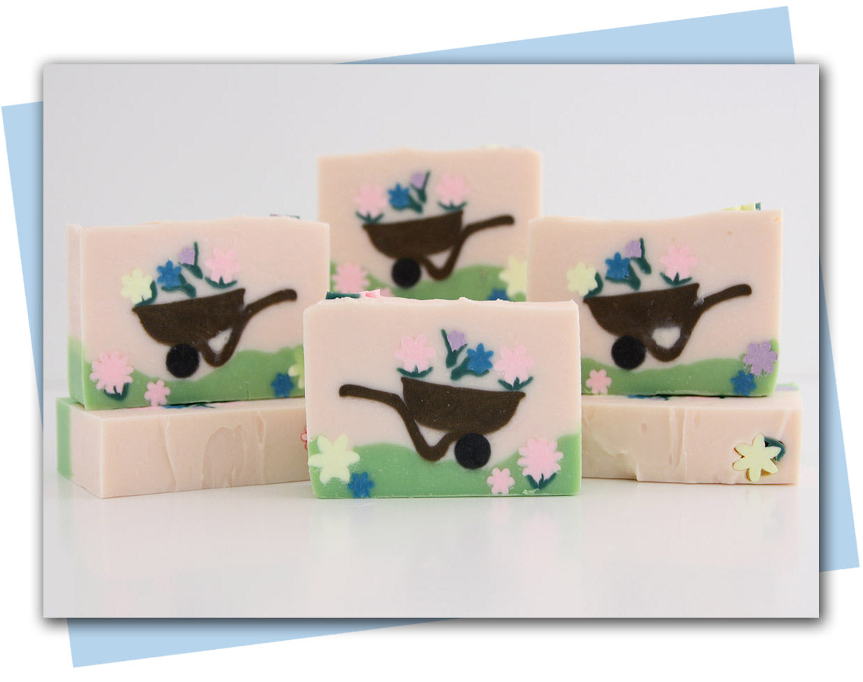 bars of soap with a wheelbarrow and flowers in it. Pink background