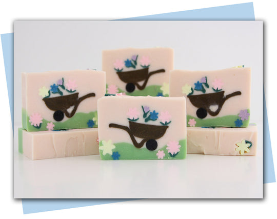 bars of soap with a wheelbarrow and flowers in it. Pink background