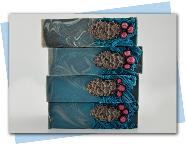 Bars of soap with pipped greenery on top with a pinecone and red holly berries added to the top.