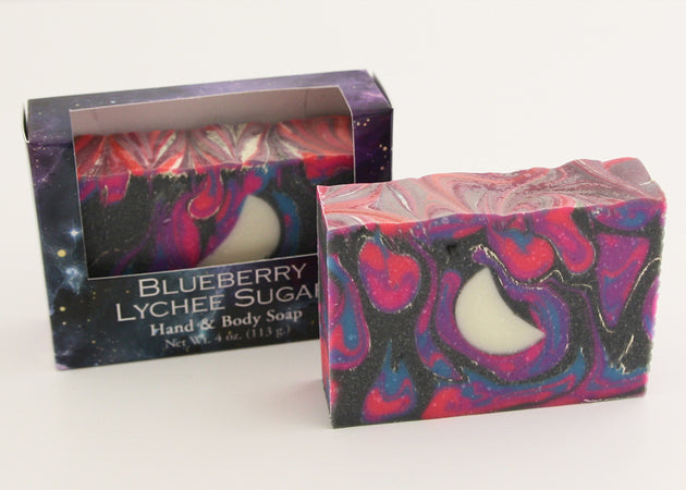 Bars of soap in custom packaging with moon embed and swirl design in black and neon colors