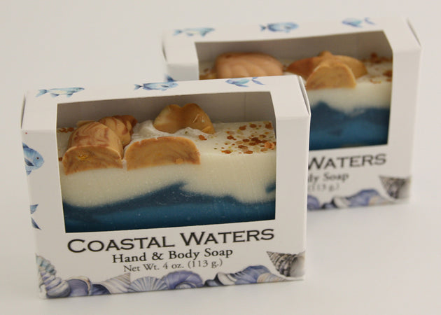 Bars of soap in custom packaging with seashells on top and ocean blue design for the bar