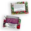 Two packaged bars of soap on a white background, one upright and one lying down. The packaging features a watercolor illustration of raspberries and green leaves, and the open lower package shows a purple soap bar labeled 'RASPBERRY VANILLA Hand & Body Soap'.