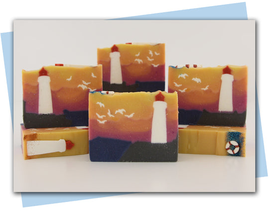 Bars of soap with a lighthouse sitting on a cliff overlooking a sunset on the ocean.