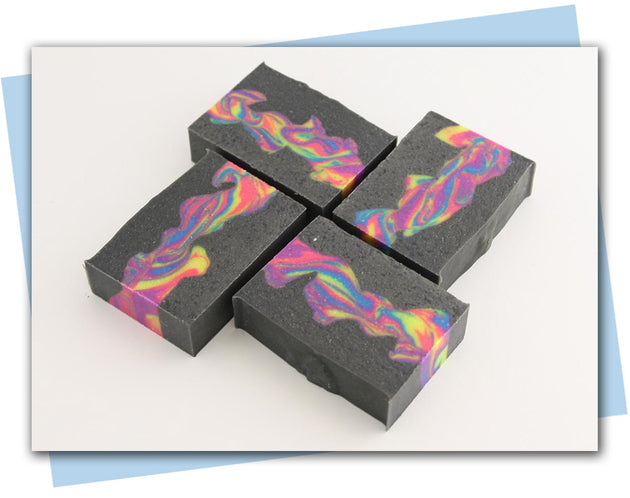 Bars of soap with three layers the outside two are black and the inside is a swirl of neon colors